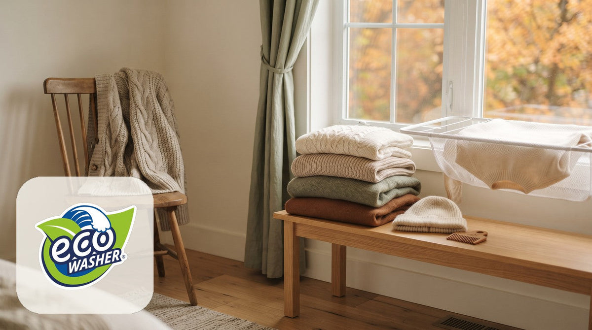 Folded knit sweaters stacked on an oak bench by a fall window, a cardigan on a chair and a sweater drying flat on a rack