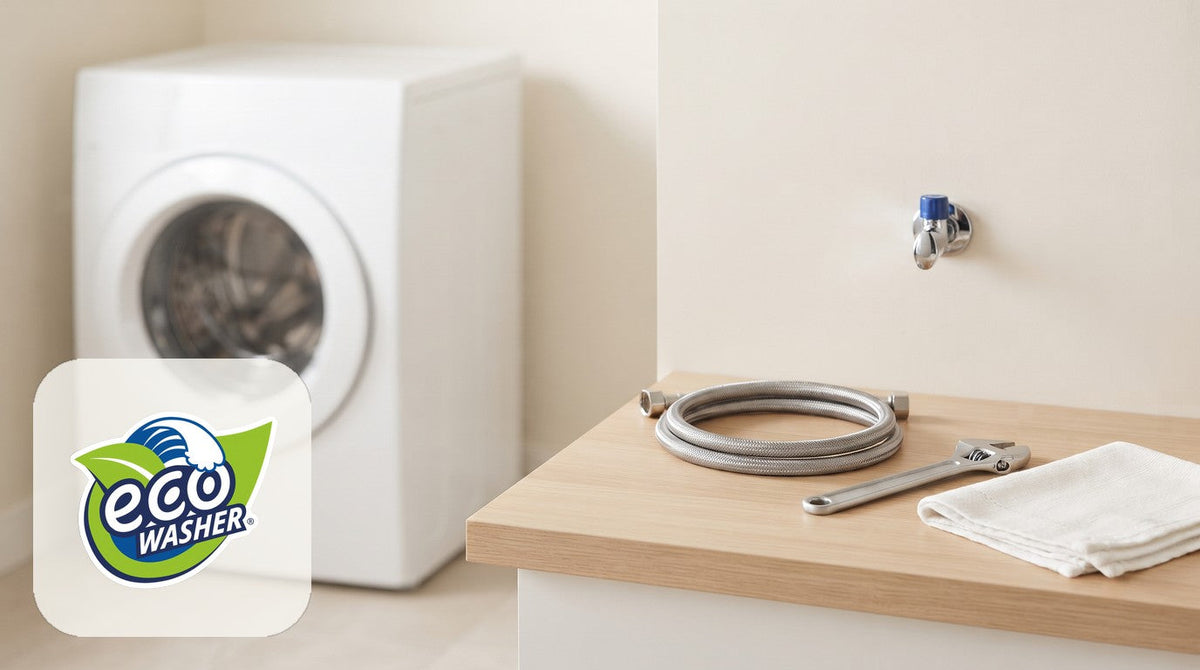 Cream laundry nook with a front-load washer, a coiled steel hose, a wrench and a folded towel on a pale oak counter
